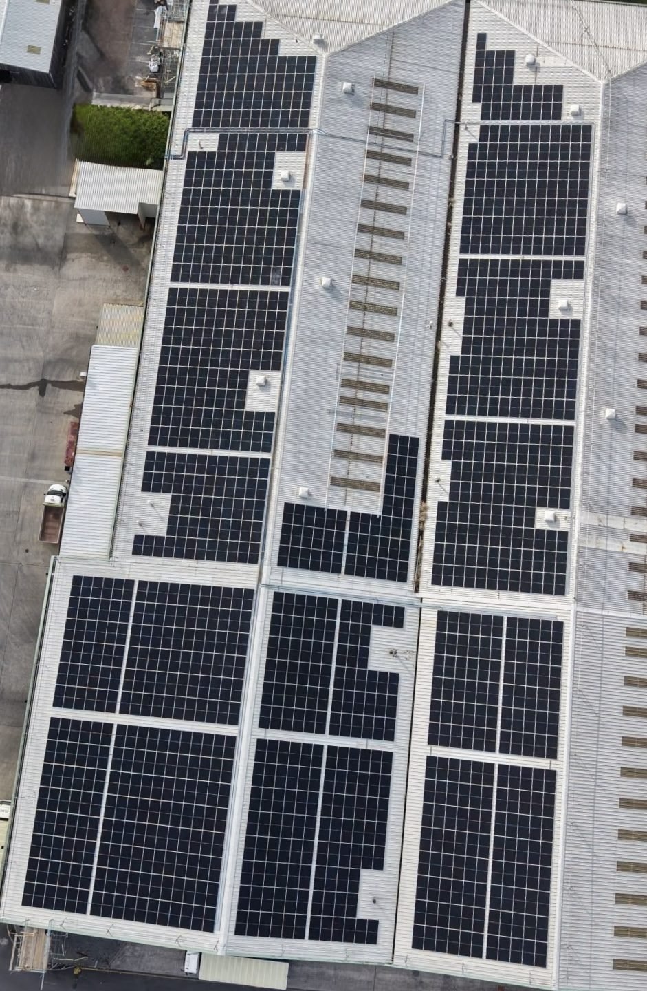Aerial view of solar panels installed across the rooftop of a large commercial building.