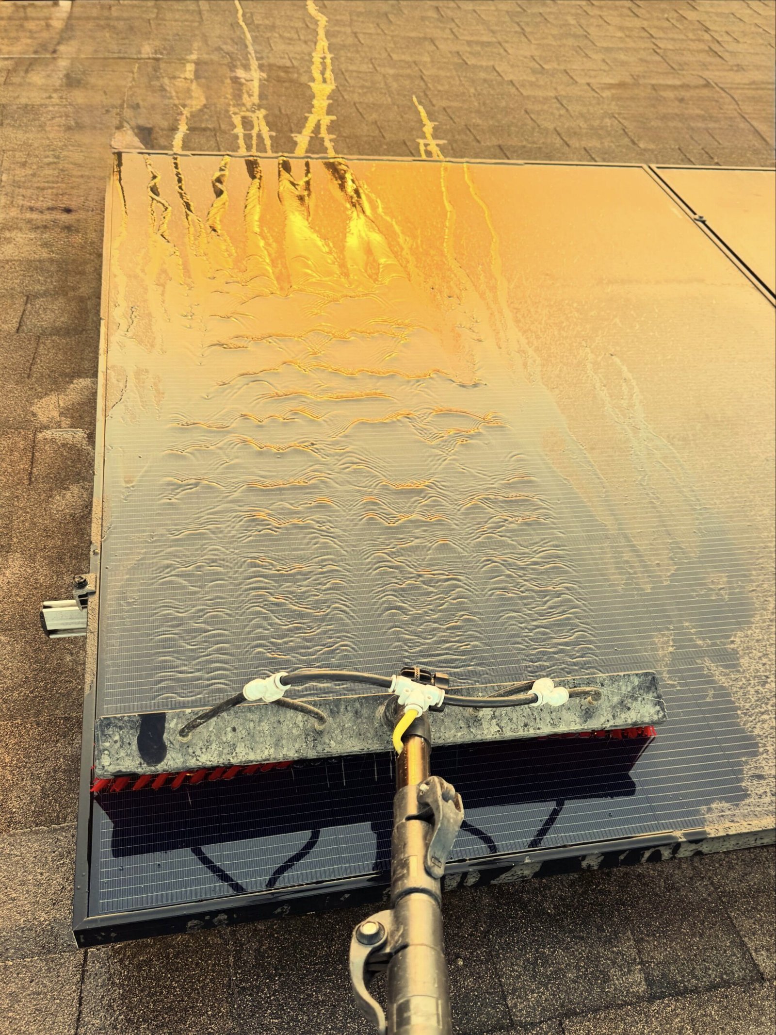 Solar panel cleaning with a water-fed brush to remove dirt and maintain rooftop solar system performance.