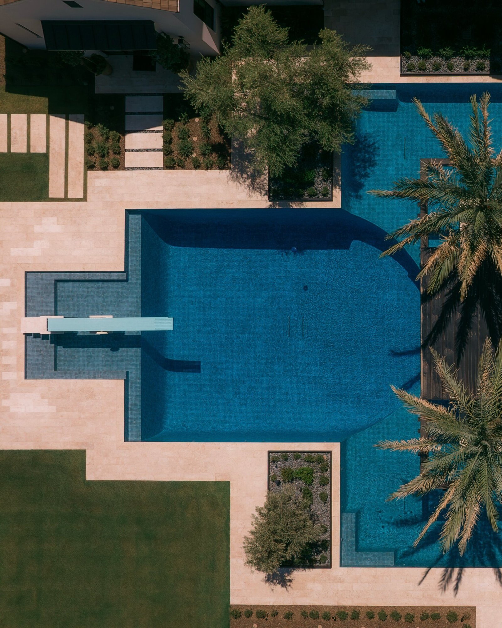 Luxury villa, swimming pool with blue tiles surrounding terrace and tropical landscaping in phuket