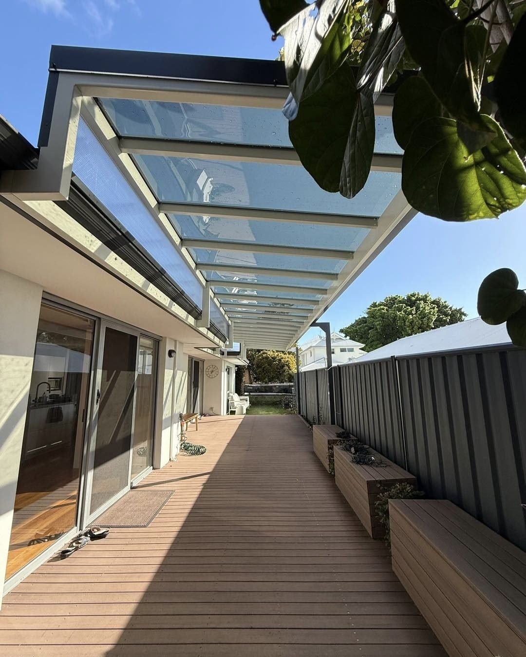 Translucent roof canopy with white metal framing covering an outdoor walkway beside a building