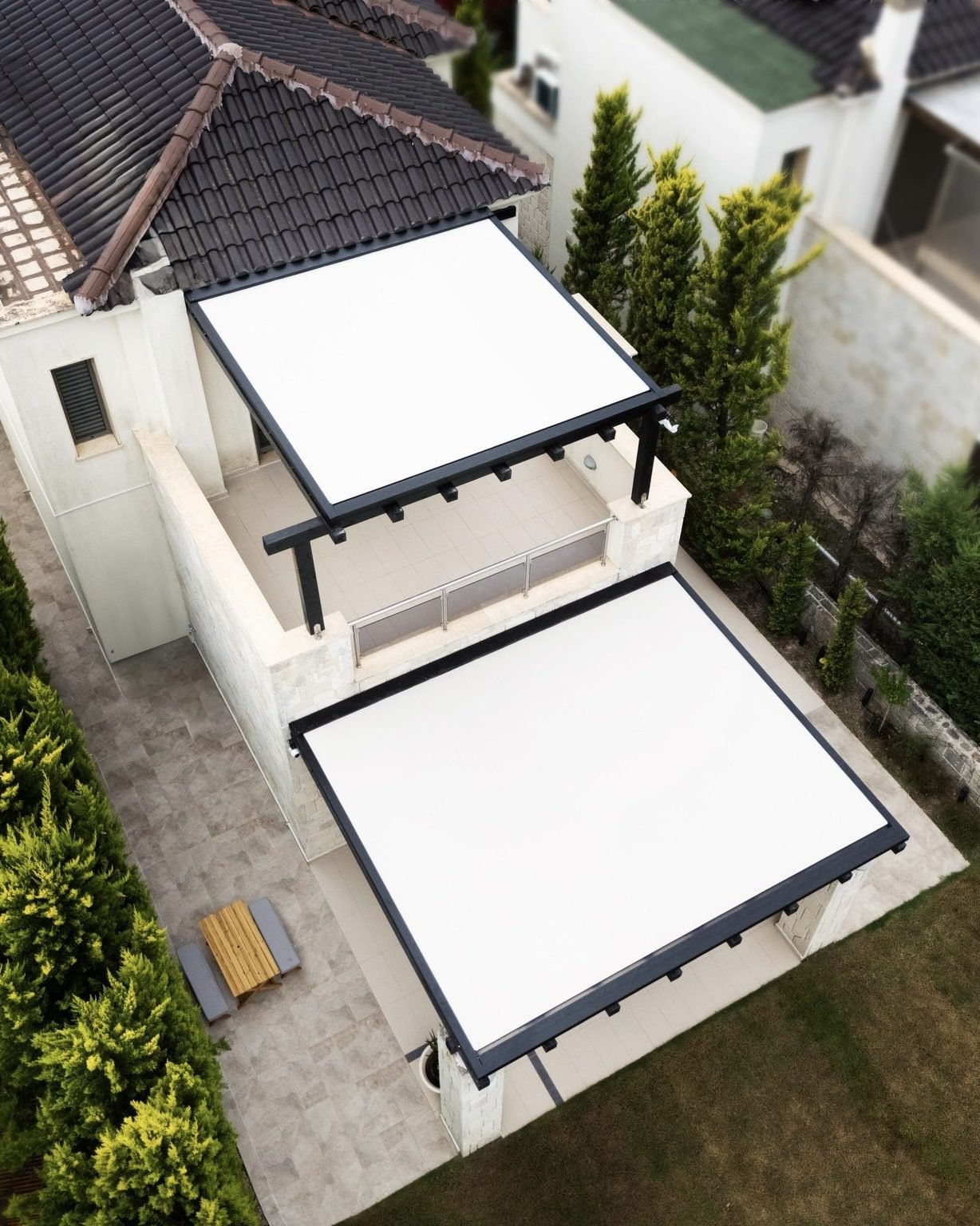 White patio awnings with dark metal frames covering outdoor terraces beside a residential building